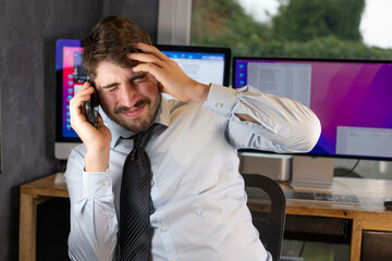 Jeune homme d'affaire ou salarié d'une entreprise fatigué et stressé ou malade qui téléphone.