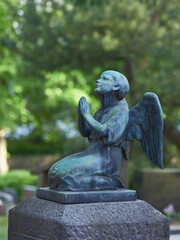 Sculpture of praying angel with wings over grave in European cemetery in Finland.