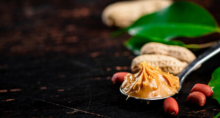 A spoonful of peanut butter on a table with leaves.
