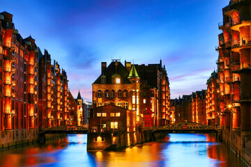 Fototapeta premium The Warehouse district Speicherstadt during twilight sunset in Hamburg, Germany. Illuminated warehouses in Hafencity quarter in Hamburg.