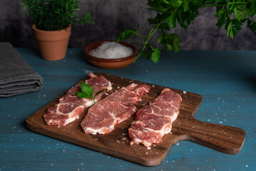 Iberian pork loin steaks on a cutting board, on a rustic wooden table, with coarse salt and ready to cook.