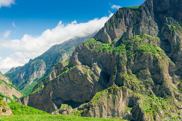 Steep vertical green rocks of the Karmadon gorge in the mountains of the northern Caucasus. Russia