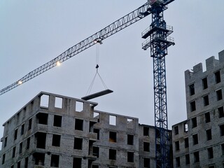 Fototapeta premium crane at a construction site lifts a concrete slab