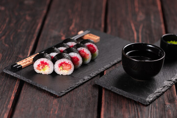 Maki sushi roll with salmon avocado and tobiko caviar served on black board close-up - Japanese food
