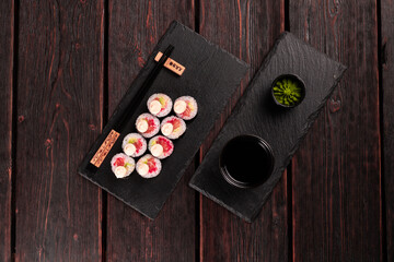 Maki sushi roll with salmon avocado and tobiko caviar served on black board top view - Japanese food