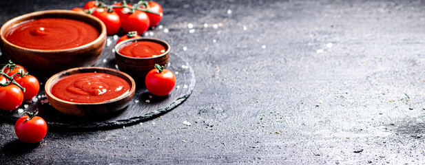 Tomato sauce in a wooden plate on a stone board with salt. 