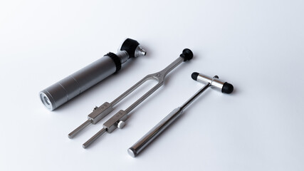 tuning fork C 128 on a white background with gradation and otorhinoscope and neurological hammer
