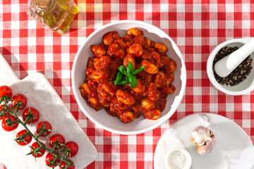 gnocchi with tomatoes and basil on a red checkered tablecloth top view