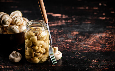 Pickled mushrooms in a glass jar on the table. 