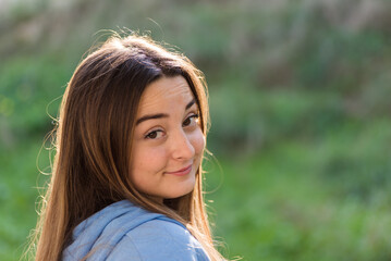 portrait of beautiful young woman, with blue t-shirt and green background, long hair, expressing surprise, joy and emotions.