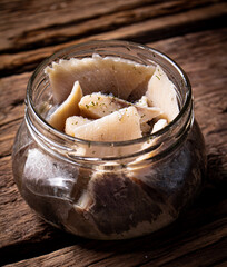 A glass jar with pieces of salted herring. 