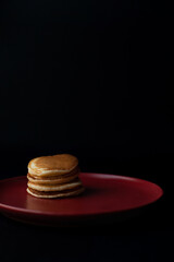 Fototapeta na wymiar Pancakes with honey on a red plate