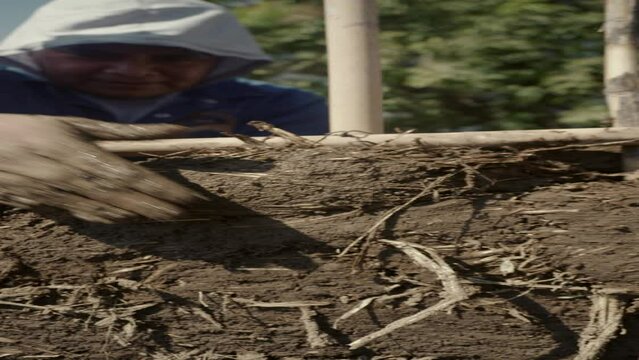 a person building with mud bioconstruction permaculture