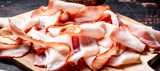 Strips of bacon on a cutting board. 
