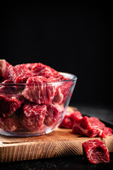 Raw sliced beef in a bowl on a cutting board.  - obrazy, fototapety, plakaty
