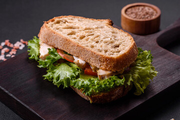 Fresh tasty sandwich with chicken, tomatoes and lettuce on a black plate