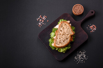 Fresh tasty sandwich with chicken, tomatoes and lettuce on a black plate