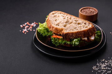 Fresh tasty sandwich with chicken, tomatoes and lettuce on a black plate