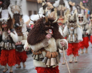 Breznik, Bulgaria - January 21, 2023: Unidentified people with traditional Kukeri costume are seen at the Festival of the Masquerade Games Surova in Breznik, Bulgaria