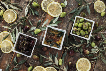 Various olives flavored with spices in cup and glass jar. Green olives, black olives. Front and top shot on wooden floor