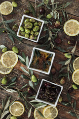 Various olives flavored with spices in cup and glass jar. Green olives, black olives. Front and top shot on wooden floor