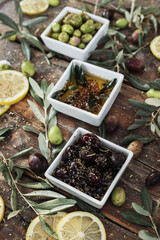 Various olives flavored with spices in cup and glass jar. Green olives, black olives. Front and top shot on wooden floor