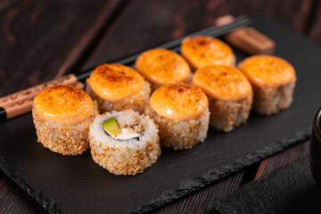 Sushi roll with eel, avocado and cream cheese served on black board close-up - Japanese food