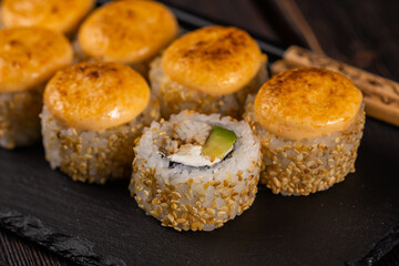 Sushi roll with eel, avocado and cream cheese served on black board close-up - Japanese food