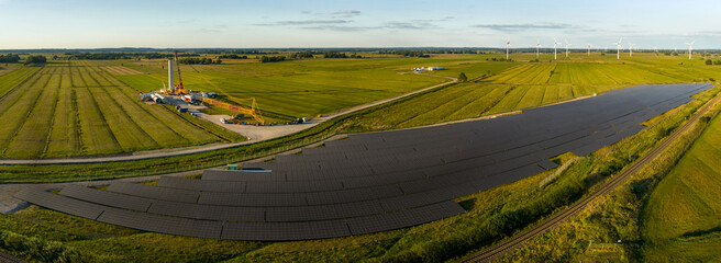 Panorama aerial view of solar energy panel photovoltaic cell and construction of wind turbine farm...
