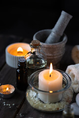 Spa setting with essential oil, candle, sea salt, pebbles, towel on dark wooden background. Massage, aromatherapy. Natural organic ingredients for relaxation, detention. Wellness in salon concept