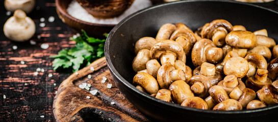 Frying pan with fried small mushrooms with parsley. 