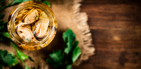 Open glass jar with pickled mussels with parsley. 