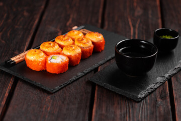 Sushi roll with crab, avocado and tobiko caviar served on black board close-up - Japanese asian food