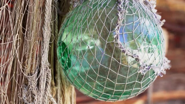 Retro fishing gear. Glass float, old fishing nets. A glass buoy on the wall of a fisherman's house.