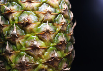 The knobby surface of a whole pineapple on the edge of the image