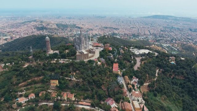 Fantastic overview aerial footage around the Expiatory Church of the Sacred Heart of Jesus (Temple Expiatori del Sagrat Cor) at the dawn in Tibidabo mountain in Barcelona.