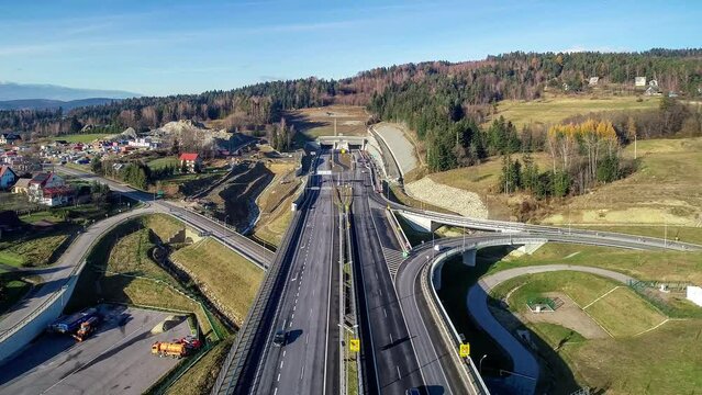 Poland. Zakopianka highway with newly opened tunnel in November 2022.  Multilevel interchange junction with traffic circles, viaducts, slip roads and traffic near Skomielna Biała. Aerial approach clip