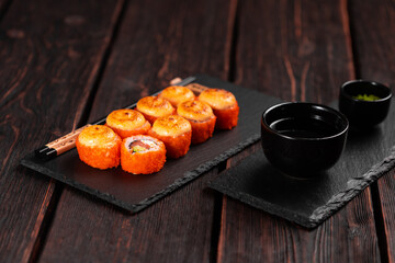 Sushi roll with salmon, avocado and tobiko caviar served on black board close-up - Japanese asian food