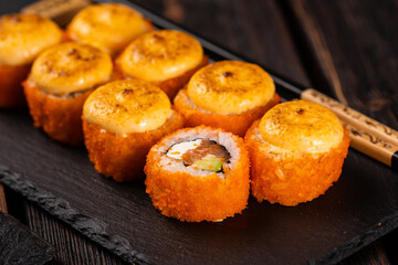 Sushi roll with salmon, avocado and tobiko caviar served on black board close-up - Japanese asian food