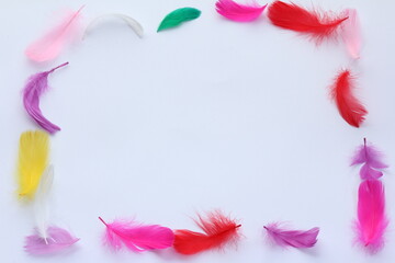 Colorful easter feathers forming a frame on white background