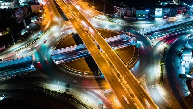 Hyperlapse time-lapse of car traffic transportation above circle roundabout road in urban downtown Asian city at night. Drone aerial view, high angle. Public transport or commuter city life concept