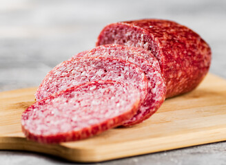 Cut into pieces of salami on a wooden cutting board. 