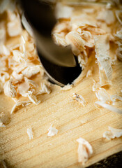 Piece of wood is drilled with shavings. 