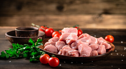 Raw pork sliced on a plate with tomatoes. 