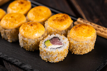 Sushi roll with tuna, avocado and tobiko caviar served on black board close-up - Japanese asian food