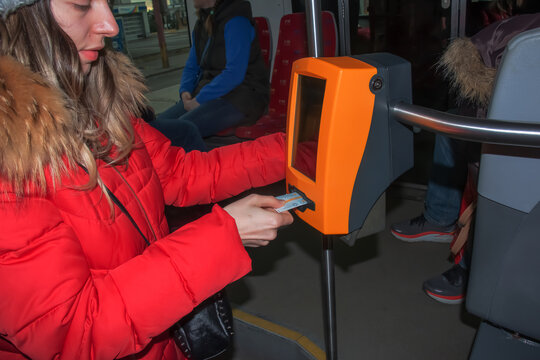 Young stylish woman using a ticket punching machine in public transport. The girl punches the ticket.
