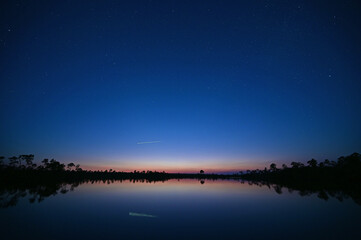 Colorful twilight, stars and airplane over Pine Glades Lake in Everglades National Park, Florida,