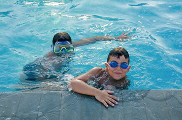 two little boys with underwater goggles in swimming pool