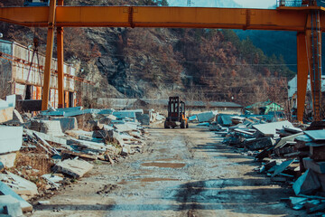 A forklift truck lifts and moves large stone blocks in a modern stone and granite processing...