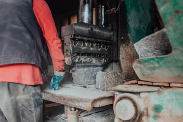A worker in heavy industry breaks stone blocks using large machines. Granite and stone processing industry.